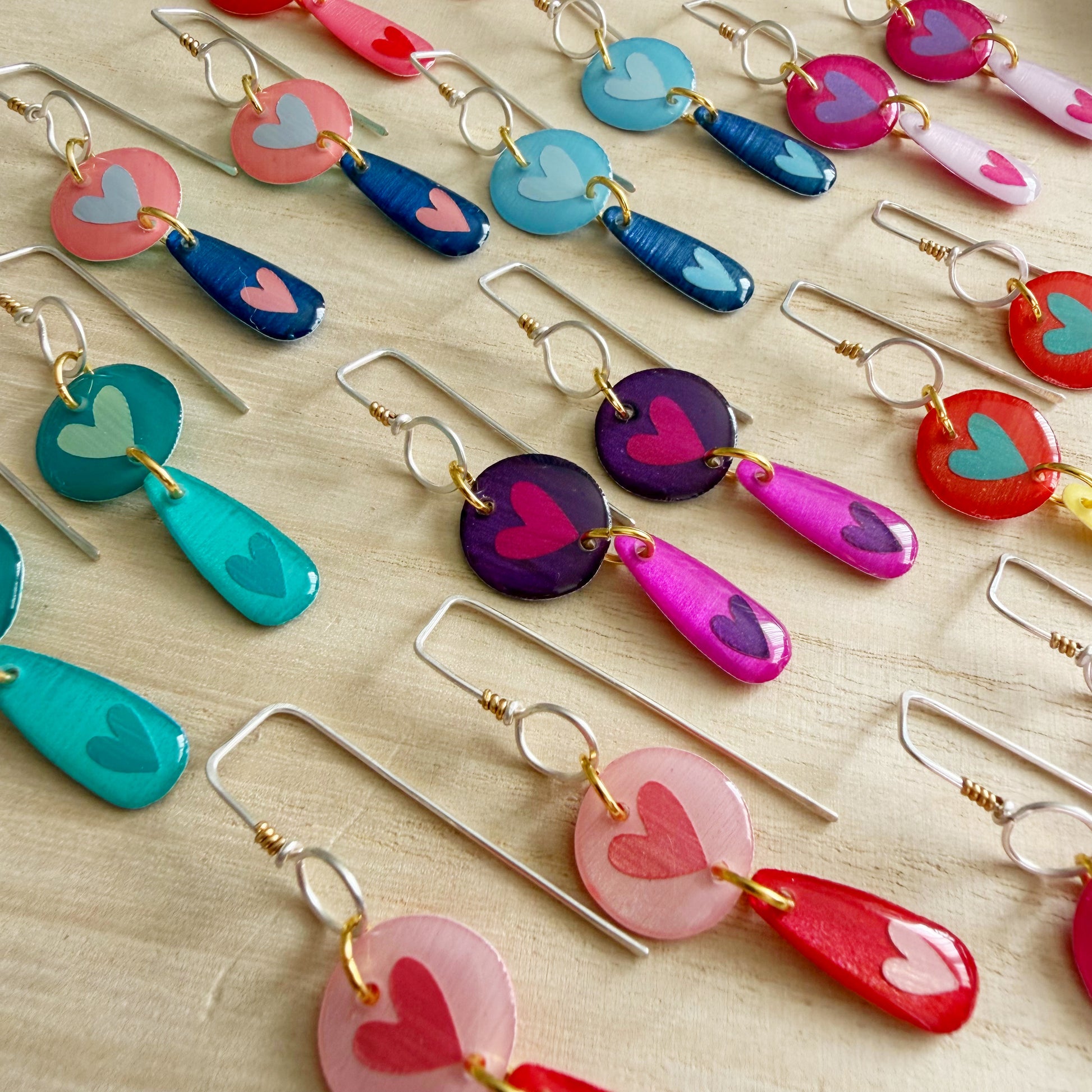 Colorful heart-shaped earrings on a light wooden surface