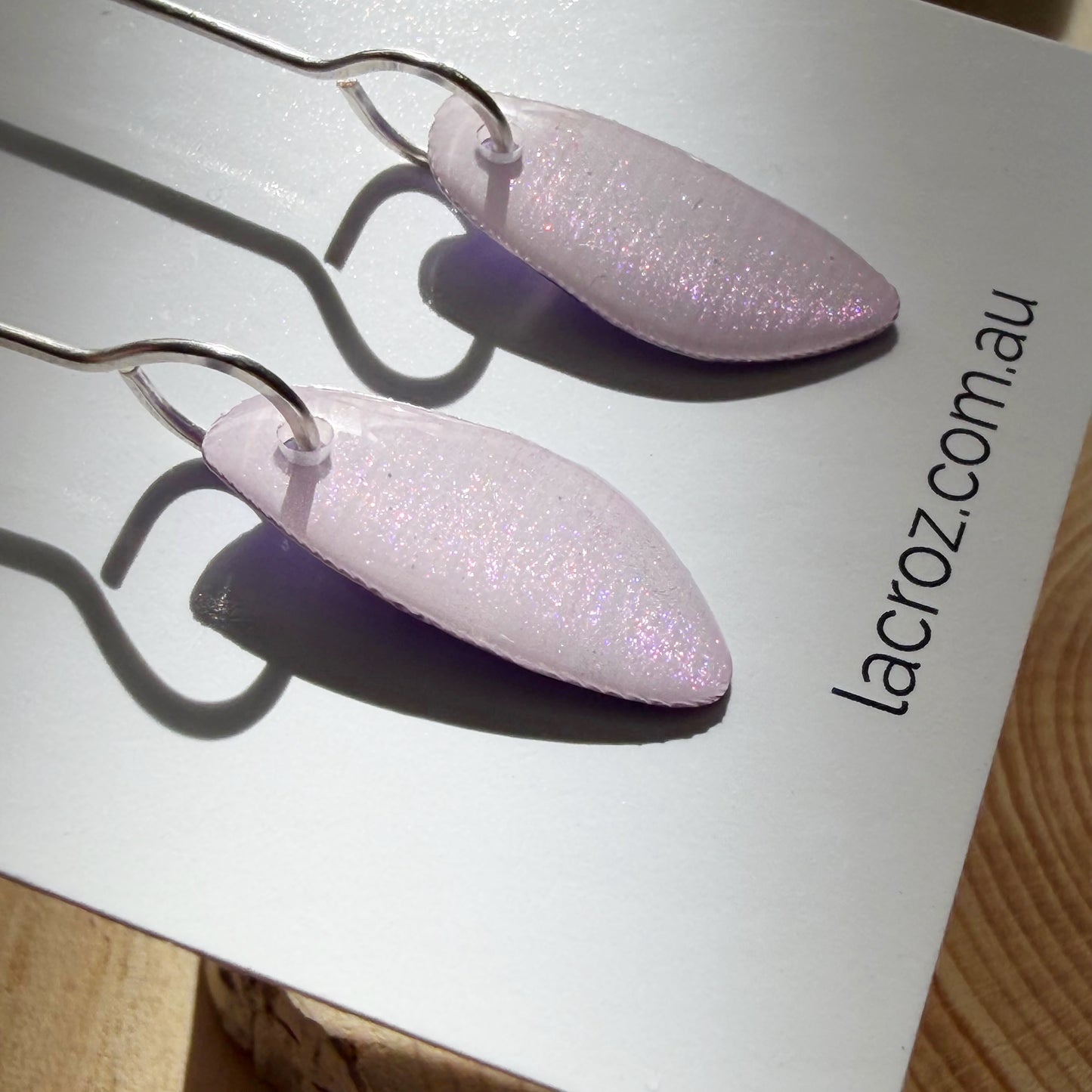 closeup of lavender coloured organic teardrop earrings on business card